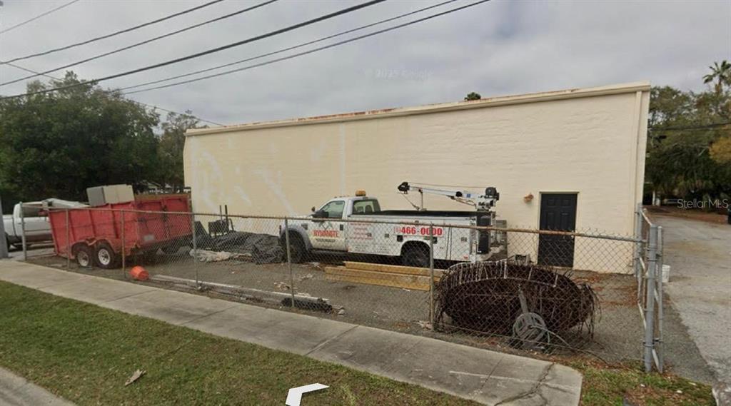 A fenced-in lot features a white commercial building, a service truck, and a red trailer — 1211 HAMLET AVENUE UNIT B, CLEARWATER, FL