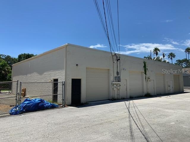 A single-story commercial building with multiple roll-up doors and a chain-link fence — 1211 HAMLET AVENUE UNIT B, CLEARWATER, FL