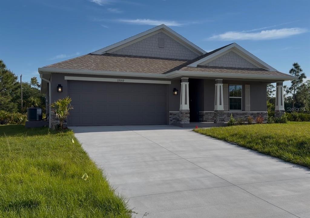 A single-story house with a gray exterior, stone accents, and a two-car garage — 12152 DUBARRY AVENUE, PORT CHARLOTTE, FL
