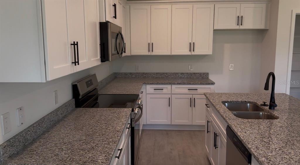 A kitchen features white cabinets, granite countertops, stainless steel appliances, and a central island — 12152 DUBARRY AVENUE, PORT CHARLOTTE, FL