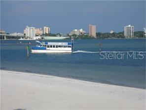 A boat travels on the water near a sandy beach with a city skyline behind — 865 S GULFVIEW BOULEVARD UNIT 207, CLEARWATER BEACH, FL