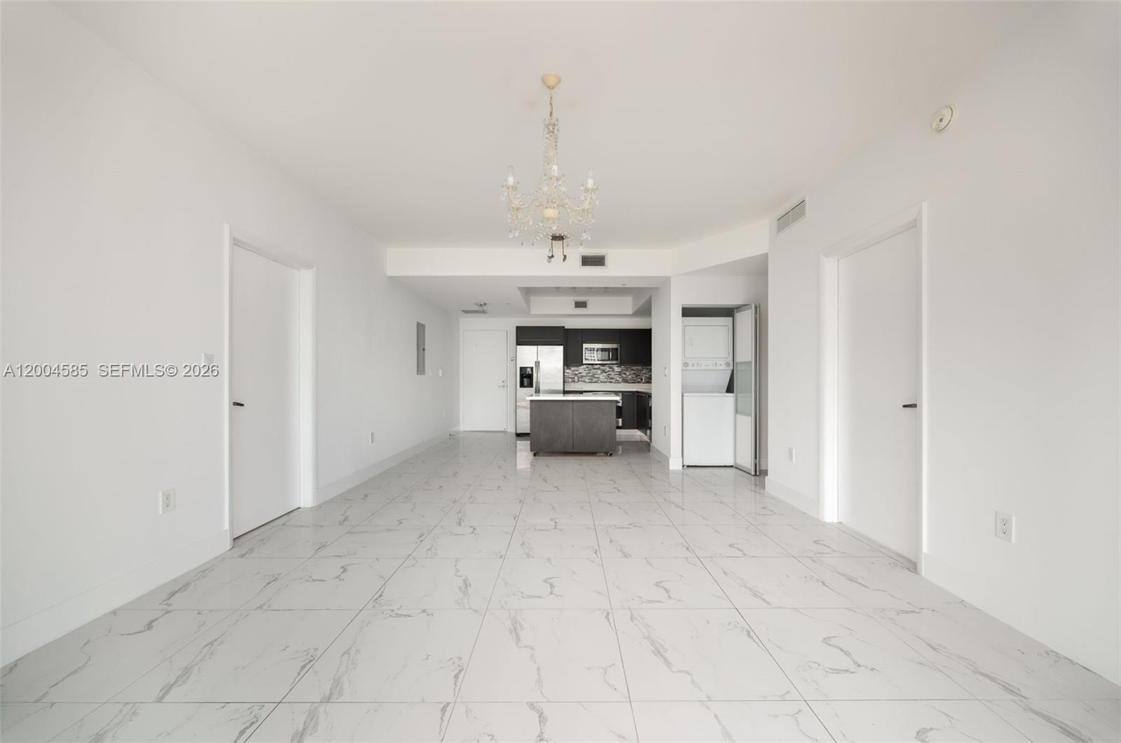 An open-concept living area features white marble-look tile flooring, a central chandelier, and a kitchen — 90 SW 3rd St # 2602, Miami FL 33130, MIAMI, FL