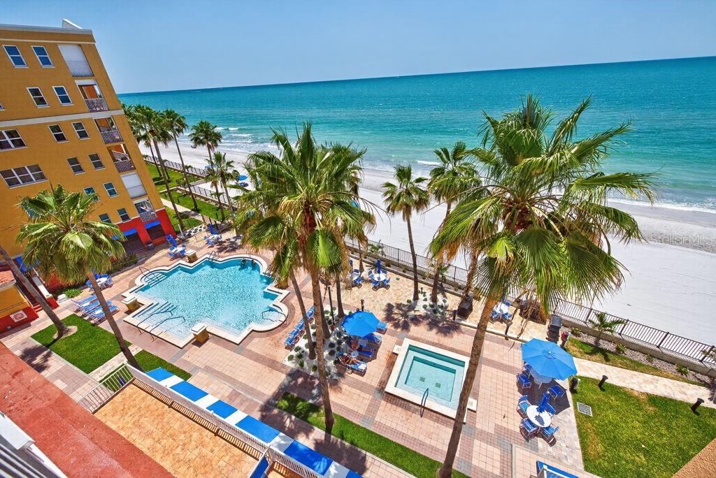 An elevated view of a beachside resort pool, hot tub, palm trees, and the ocean — 16500 GULF BOULEVARD UNIT 654, NORTH REDINGTON BEACH, FL