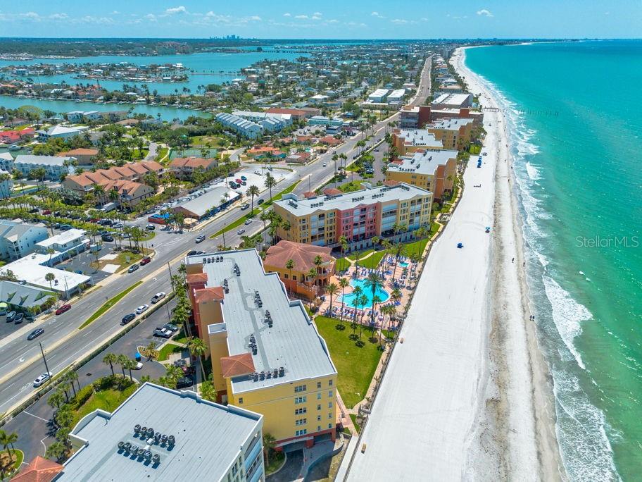 An aerial view shows beachfront multi-story buildings, a swimming pool, and a white sand beach — 16500 GULF BOULEVARD UNIT 654, NORTH REDINGTON BEACH, FL
