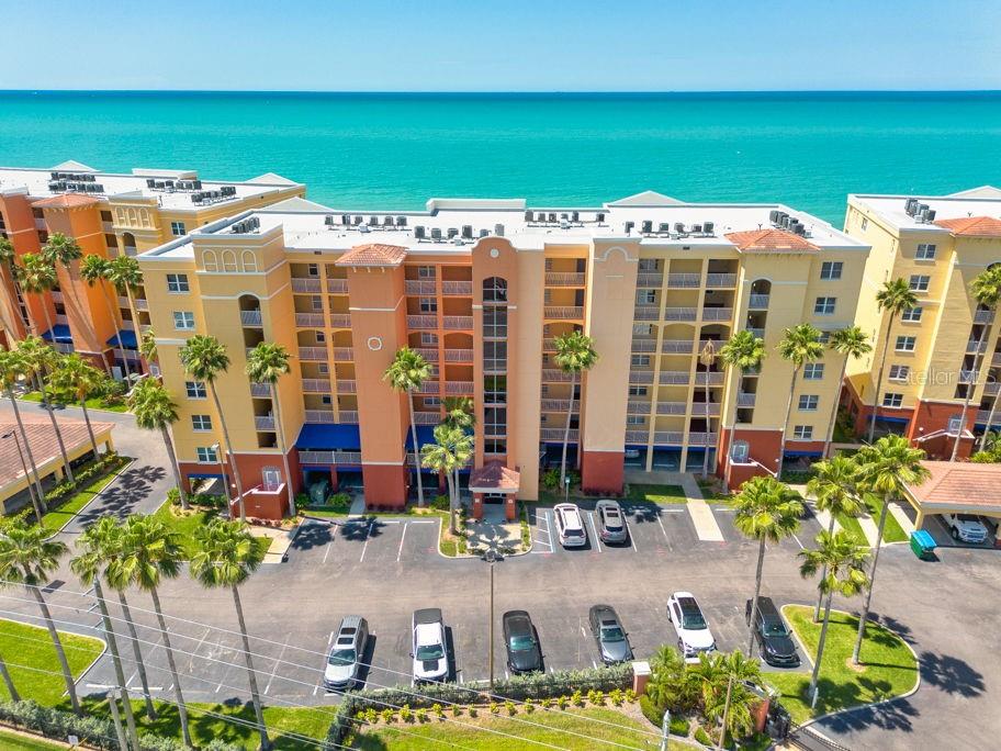 An aerial view of a multi-story apartment building with palm trees and a parking lot — 16500 GULF BOULEVARD UNIT 654, NORTH REDINGTON BEACH, FL