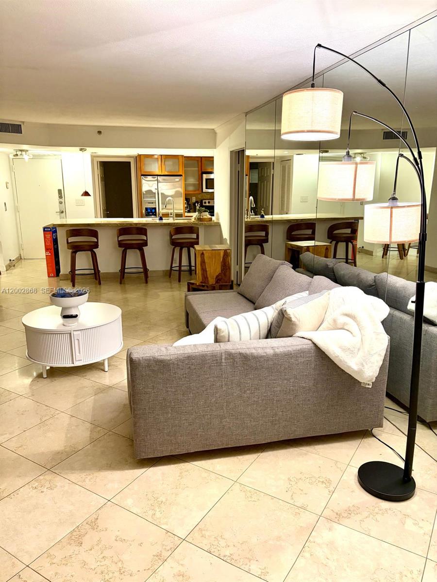 A living room with a gray sofa, white coffee table, and a breakfast bar area — 1717 N Bayshore Dr # 1236, Miami FL 33132, MIAMI, FL