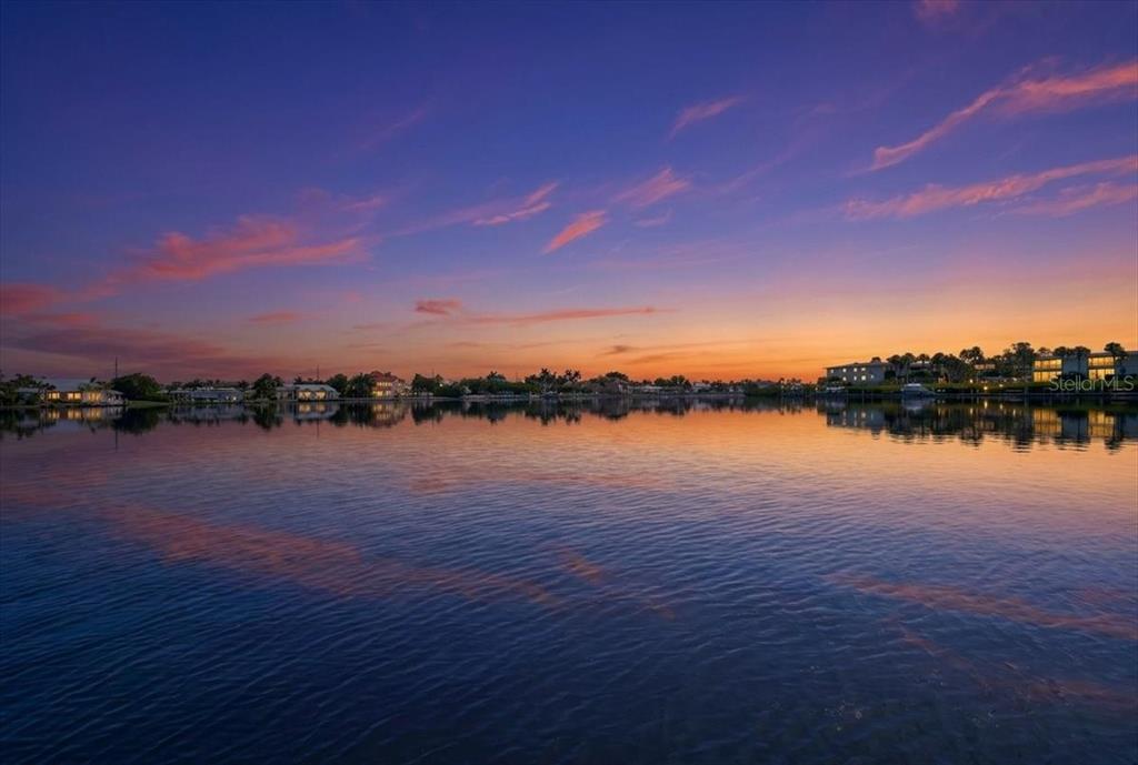A calm body of water reflects a vibrant sunset sky with distant waterfront homes — 17 SEASIDE COURT, HOLMES BEACH, FL