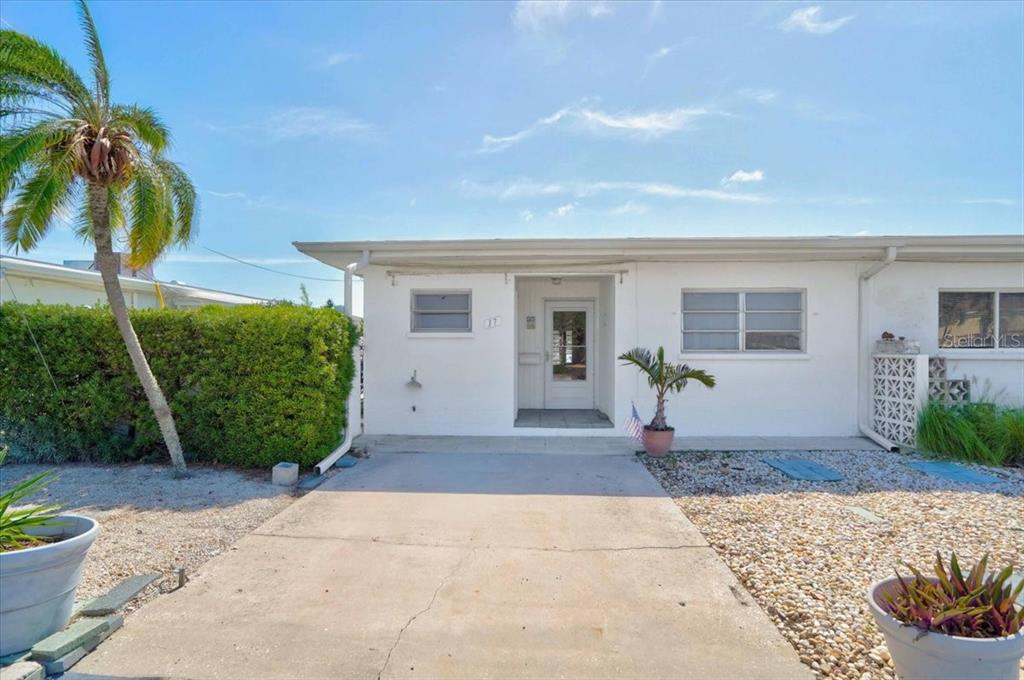 The exterior of a white, single-story residential building features a concrete driveway and landscaping — 17 SEASIDE COURT, HOLMES BEACH, FL