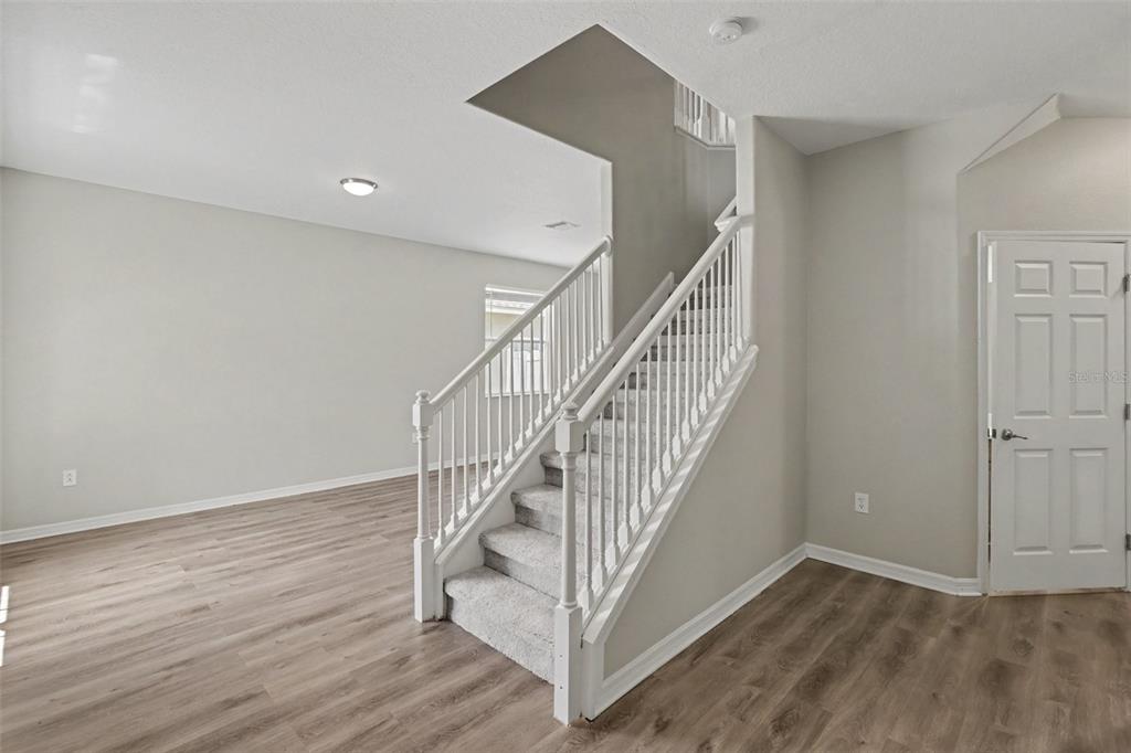 A staircase with white railings and carpeted steps sits in a room with wood-look flooring — 5729 SWEET WILLIAM TERRACE, LAND O LAKES, FL