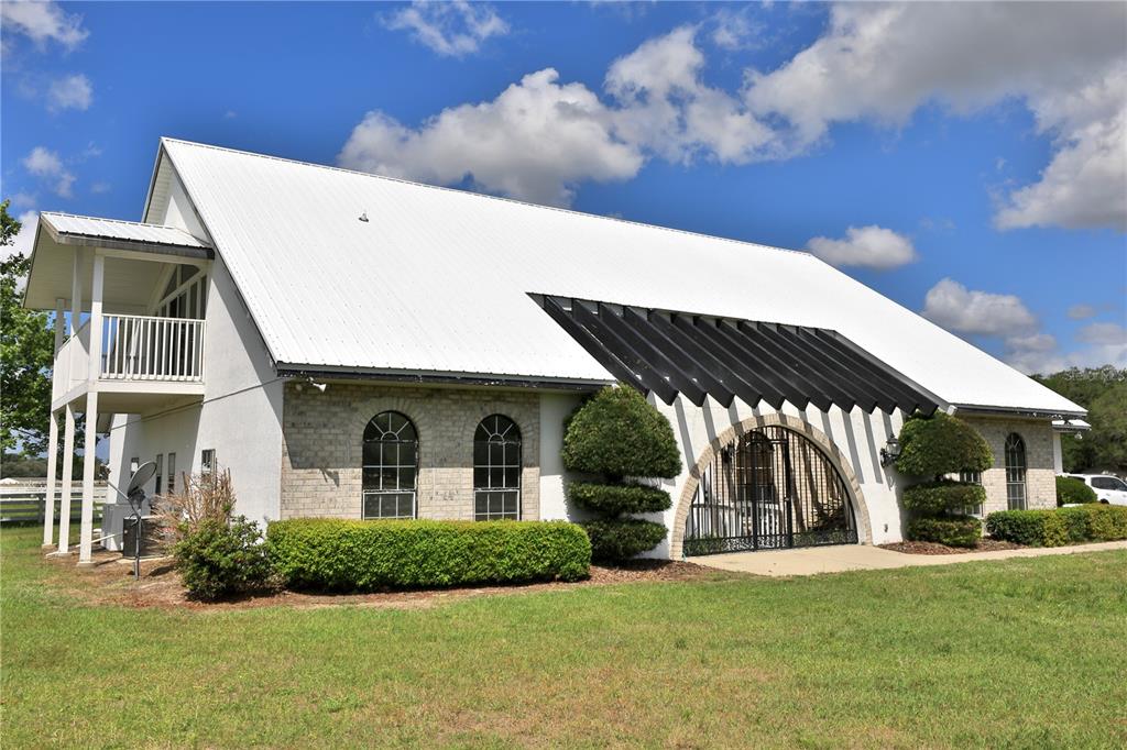 A white building with a metal roof, brick facade, arched windows, and a covered balcony — 4450 SE 216TH AVENUE, MORRISTON, FL