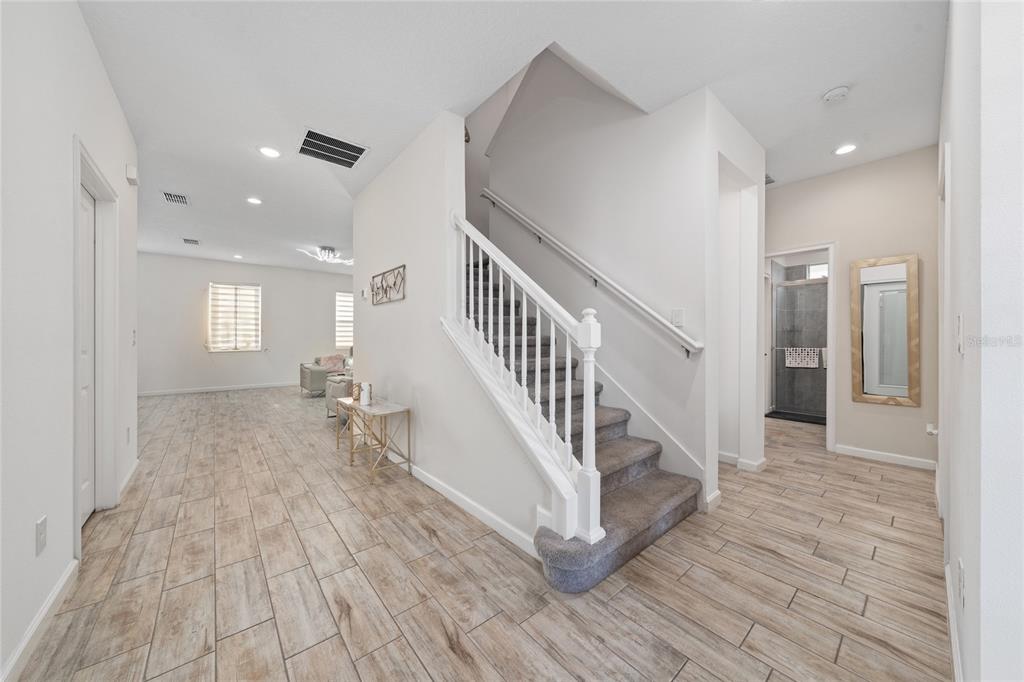 A bright entryway features wood-look tile flooring, a carpeted staircase, and an open living area — 1369 YORKDALE ROAD, DAVENPORT, FL