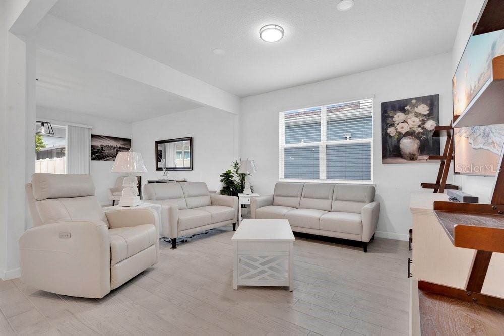 A bright living room features light-colored furniture, a white coffee table, and light wood flooring — 1457 GRAND PALM DRIVE, ORLANDO, FL