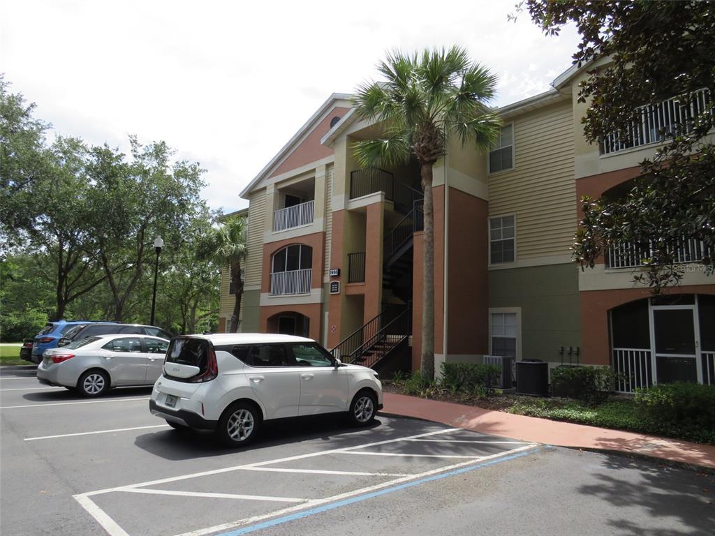 A three-story apartment building exterior with a parking lot and two cars in front — 1950 SUMMER CLUB DRIVE UNIT 306, OVIEDO, FL