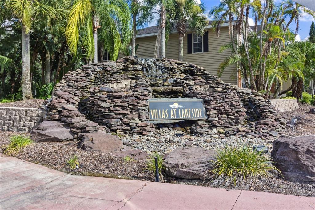 A stone waterfall feature displays a sign for Villas at Lakeside in front of buildings — 1950 SUMMER CLUB DRIVE UNIT 306, OVIEDO, FL