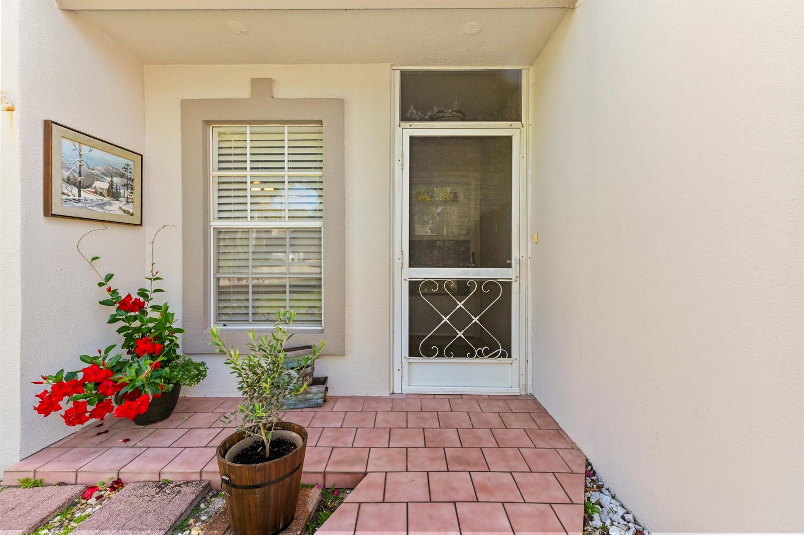 A tiled entryway features a white screen door, a window, and potted plants — 9244 Flynn Circle # 2, Boca Raton FL 33496, BOCA RATON, FL