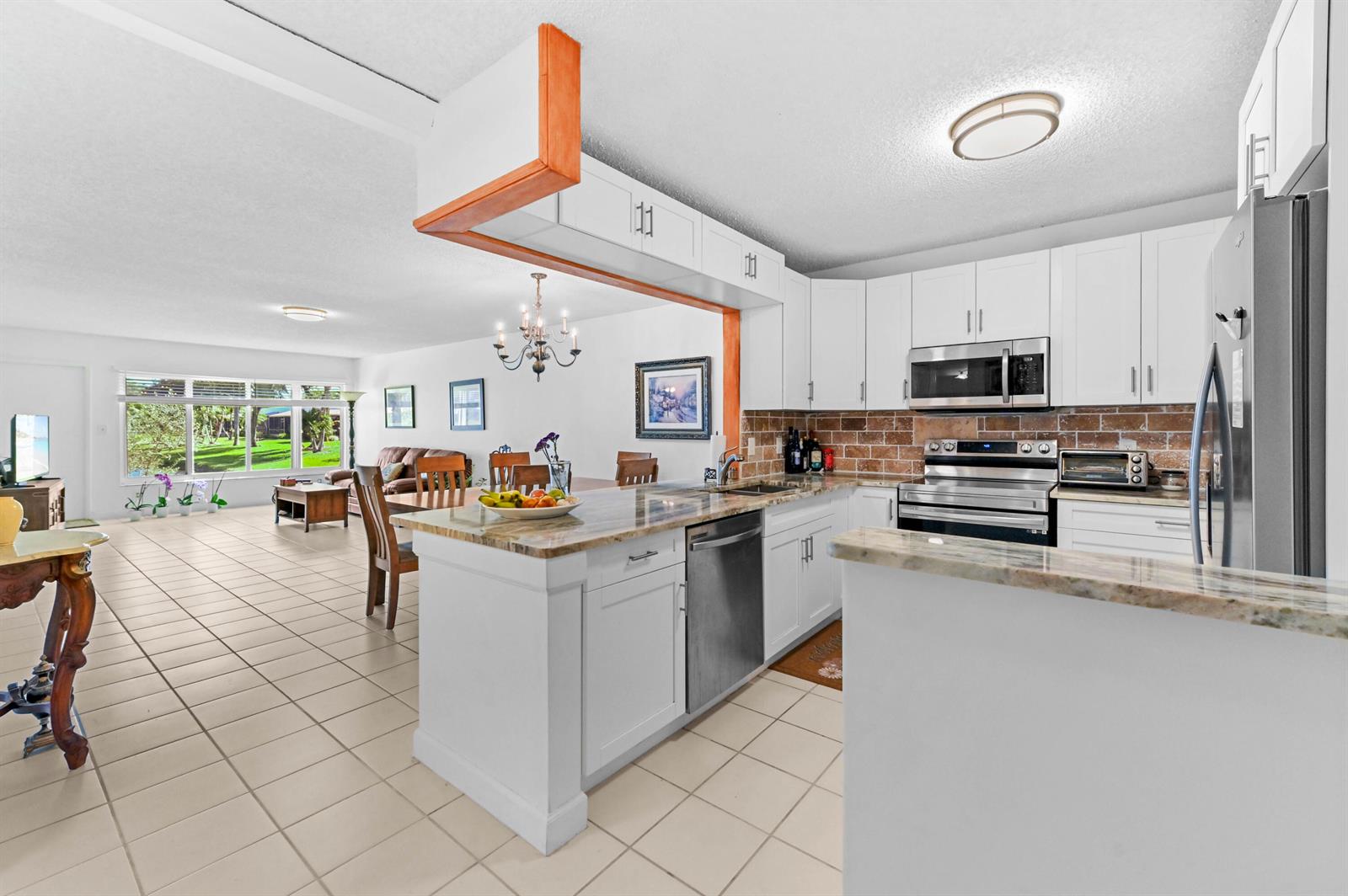 A kitchen with white cabinets and granite countertops opens into a dining and living area — 9244 Flynn Circle # 2, Boca Raton FL 33496, BOCA RATON, FL