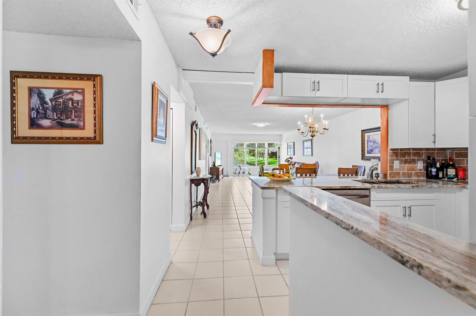 A view from a kitchen looking down a tiled hallway toward a living area — 9244 Flynn Circle # 2, Boca Raton FL 33496, BOCA RATON, FL