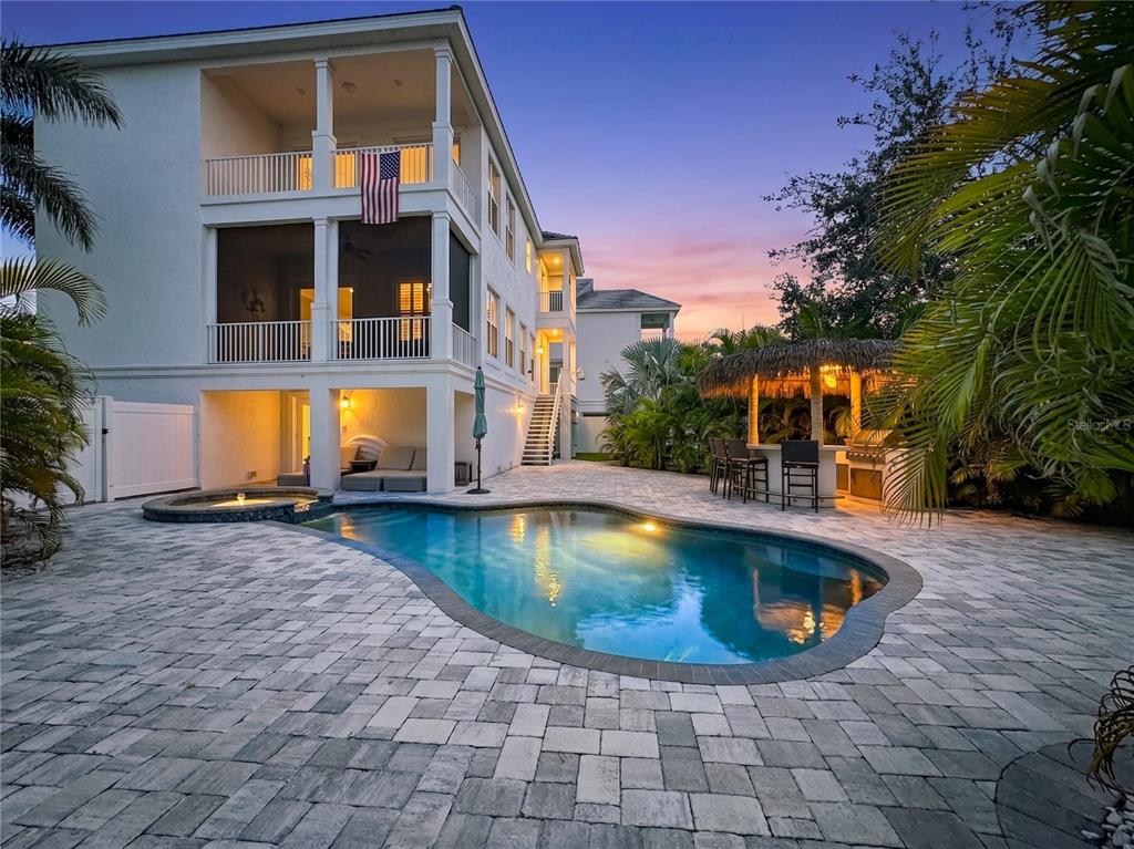 A multi-story house with a pool, hot tub, and tiki bar on a paved patio — 6925 BOCHI CIRCLE, SARASOTA, FL