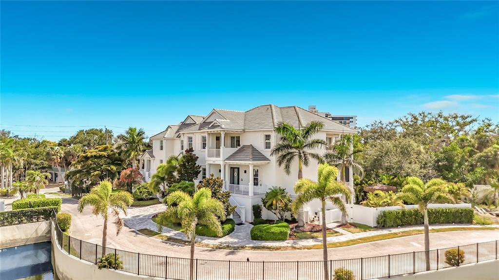 A large, multi-story white house with a tiled roof sits behind a curved metal fence — 6925 BOCHI CIRCLE, SARASOTA, FL