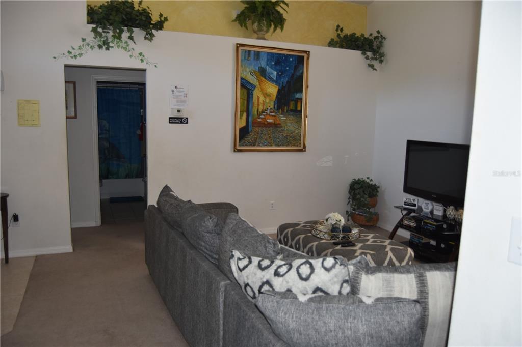 A living room features a gray sofa, a patterned ottoman, and a framed wall painting — 4442 GREAT HARBOR LANE, KISSIMMEE, FL