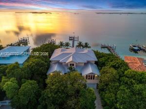 An aerial view shows a house surrounded by trees near a dock at sunset — 104 Coastal Dr, Key Largo FL 33037, KEY LARGO, FL