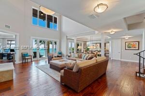 A spacious living room features high ceilings, hardwood floors, and large windows overlooking the ocean — 104 Coastal Dr, Key Largo FL 33037, KEY LARGO, FL