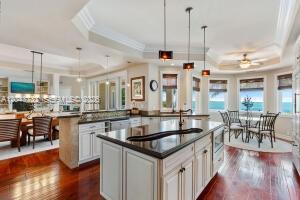 A kitchen with white cabinetry, a dark island, and hardwood floors overlooks the ocean — 104 Coastal Dr, Key Largo FL 33037, KEY LARGO, FL
