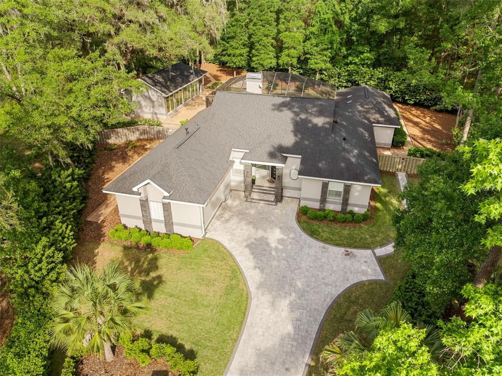 An aerial view shows a single-story house with a paved driveway and a screened pool — 8701 SW 46TH LANE, GAINESVILLE, FL