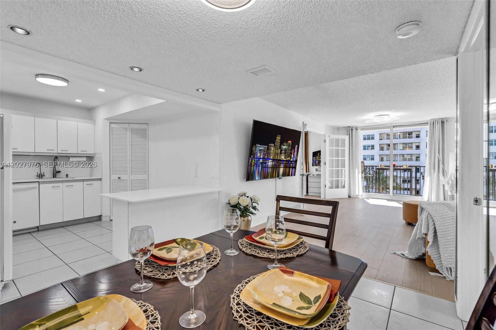 A dining area with a dark wood table overlooks an open kitchen and living space — 9273 Collins Ave # 503, Surfside FL 33154, SURFSIDE, FL