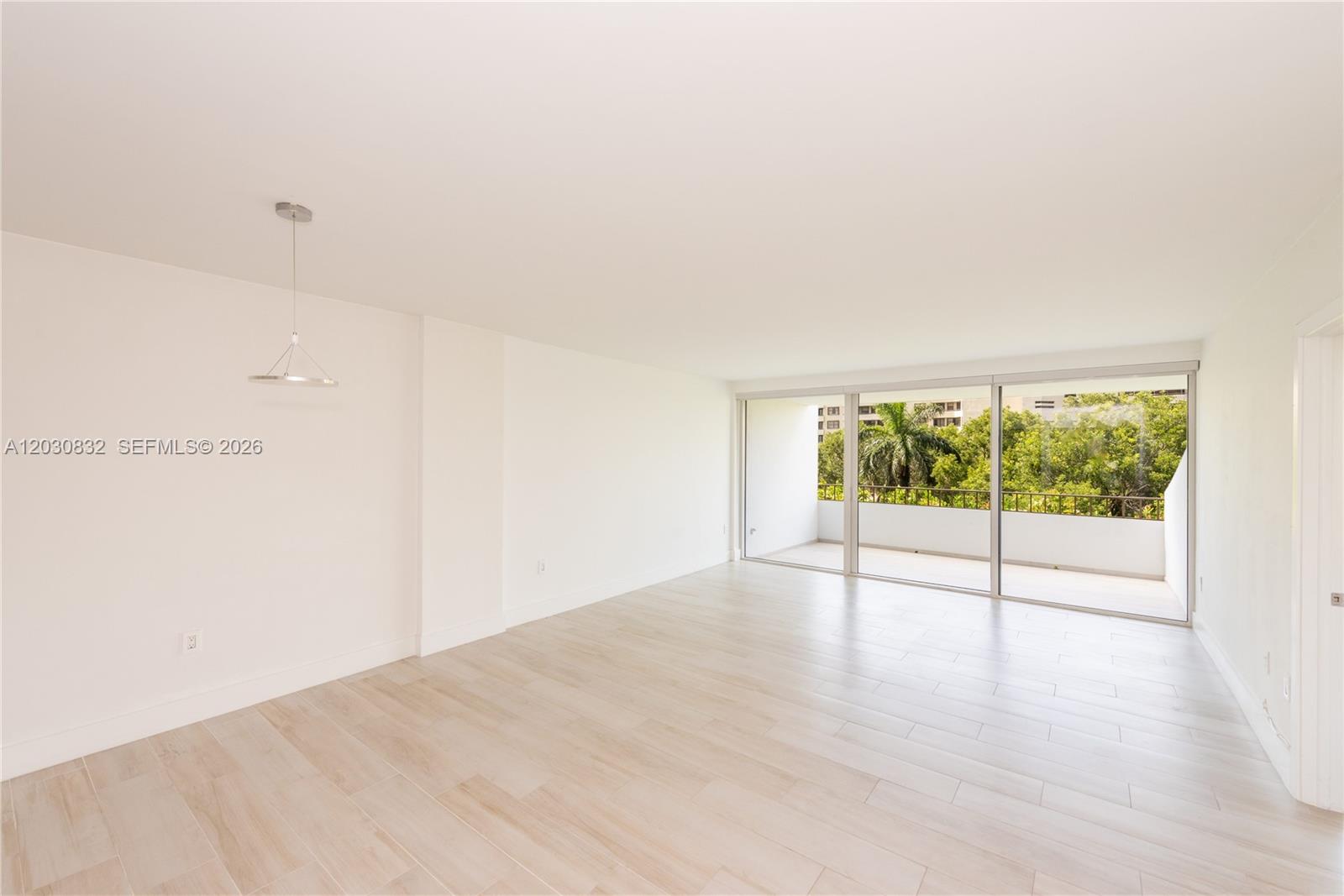 An empty room with light wood-look tile flooring and a sliding glass door to a balcony — 155 Ocean Lane Dr # 403, Key Biscayne FL 33149, KEY BISCAYNE, FL