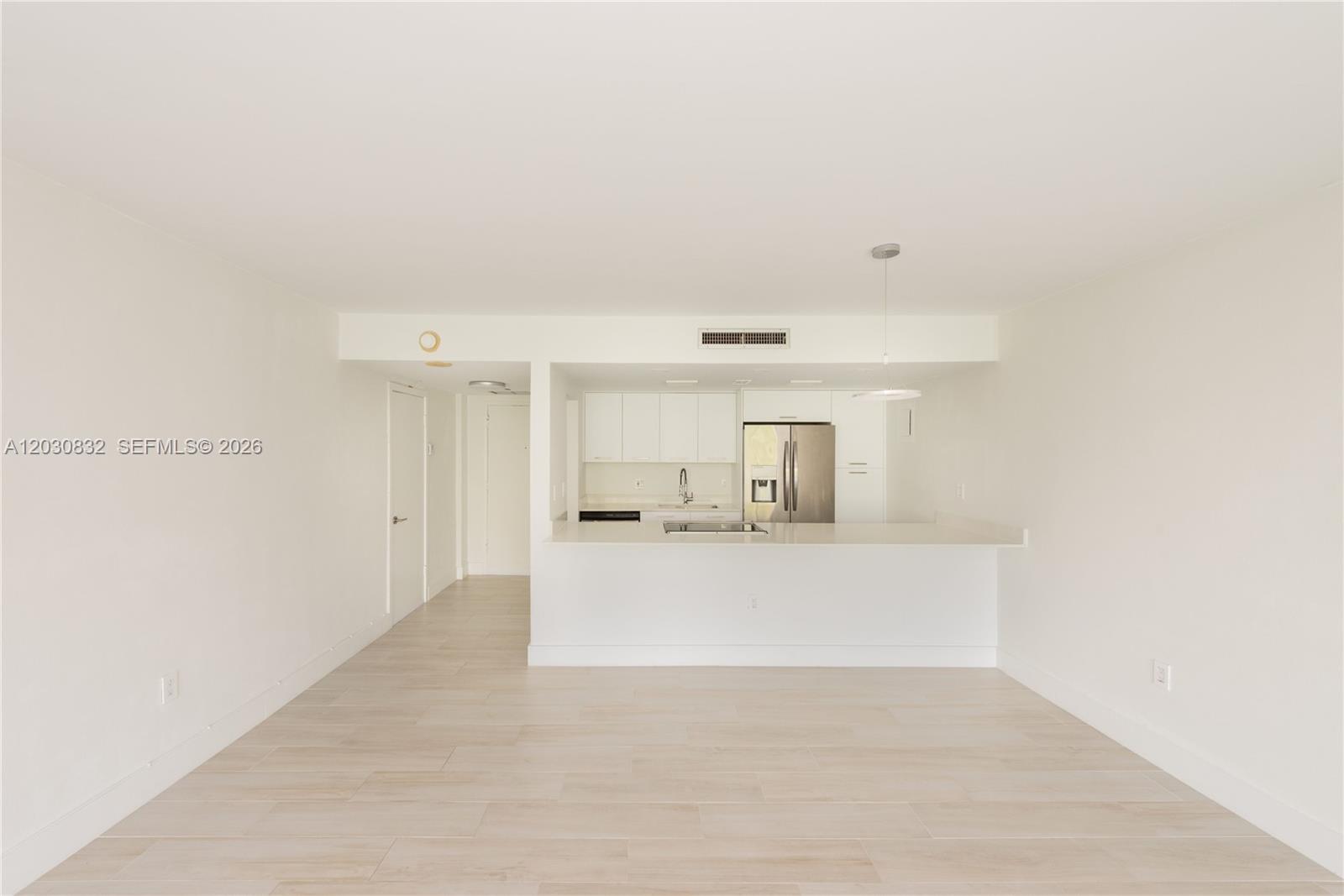 This open-concept kitchen features white cabinetry, stainless steel appliances, and light-toned wood-look flooring — 155 Ocean Lane Dr # 403, Key Biscayne FL 33149, KEY BISCAYNE, FL