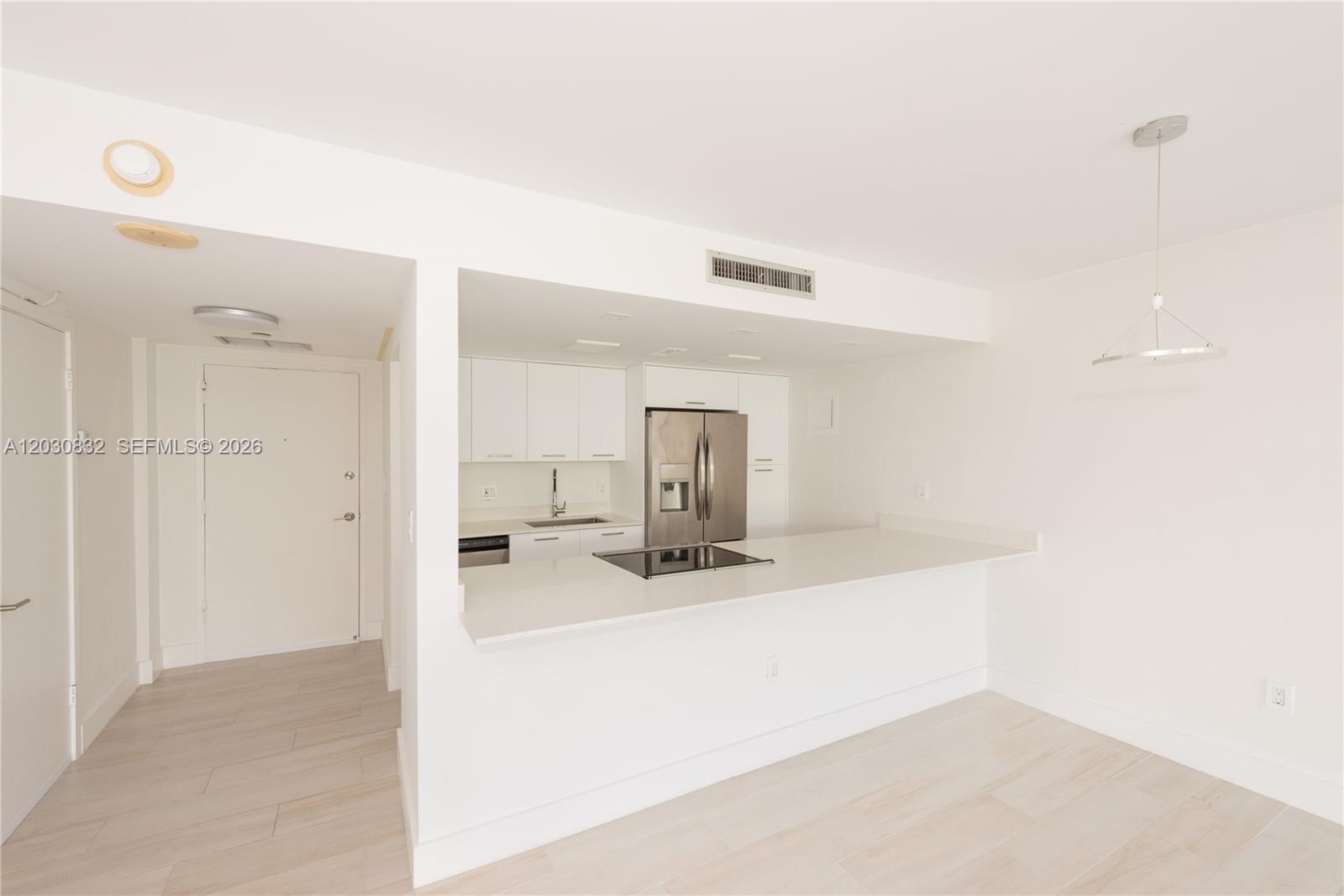 A modern kitchen features white cabinetry, stainless steel appliances, and a white breakfast bar — 155 Ocean Lane Dr # 403, Key Biscayne FL 33149, KEY BISCAYNE, FL