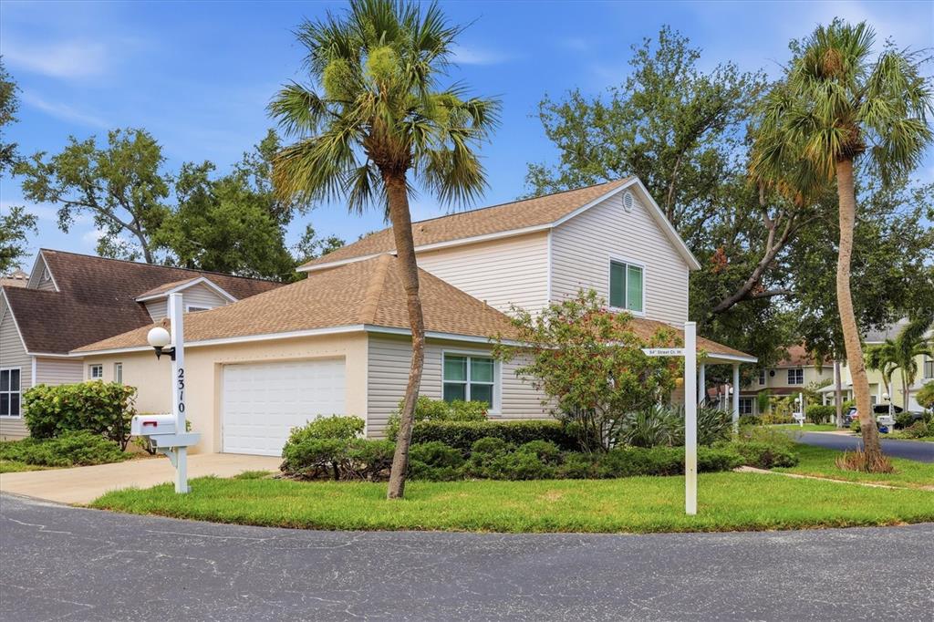 A two-story house with light-colored siding, a garage, and palm trees in the front yard — 2310 64TH STREET COURT W, BRADENTON, FL