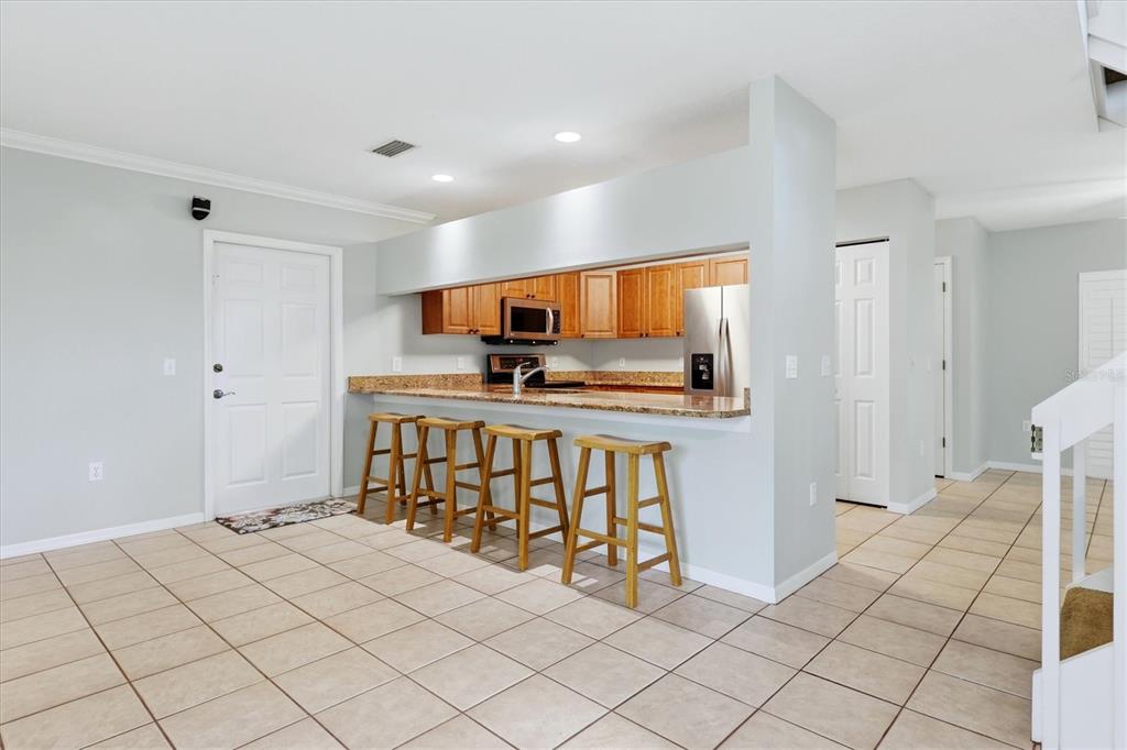 A kitchen with wooden cabinets and granite countertops features a breakfast bar with four stools — 2310 64TH STREET COURT W, BRADENTON, FL