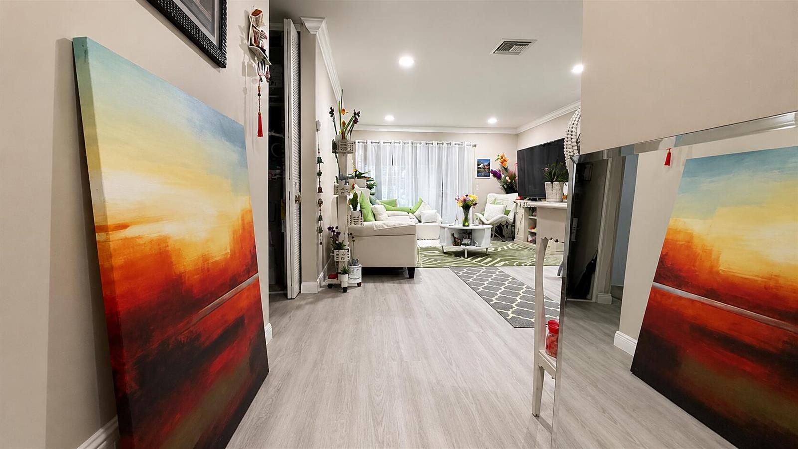 A hallway leads into a living room with light wood flooring and a large painting — 2716 E Emory Dr Drive E # D, West Palm Beach FL 33415, WEST PALM BEACH, FL