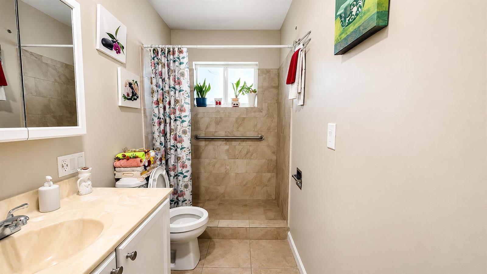 A bathroom features a vanity, a toilet, and a tiled walk-in shower with a grab bar — 2716 E Emory Dr Drive E # D, West Palm Beach FL 33415, WEST PALM BEACH, FL
