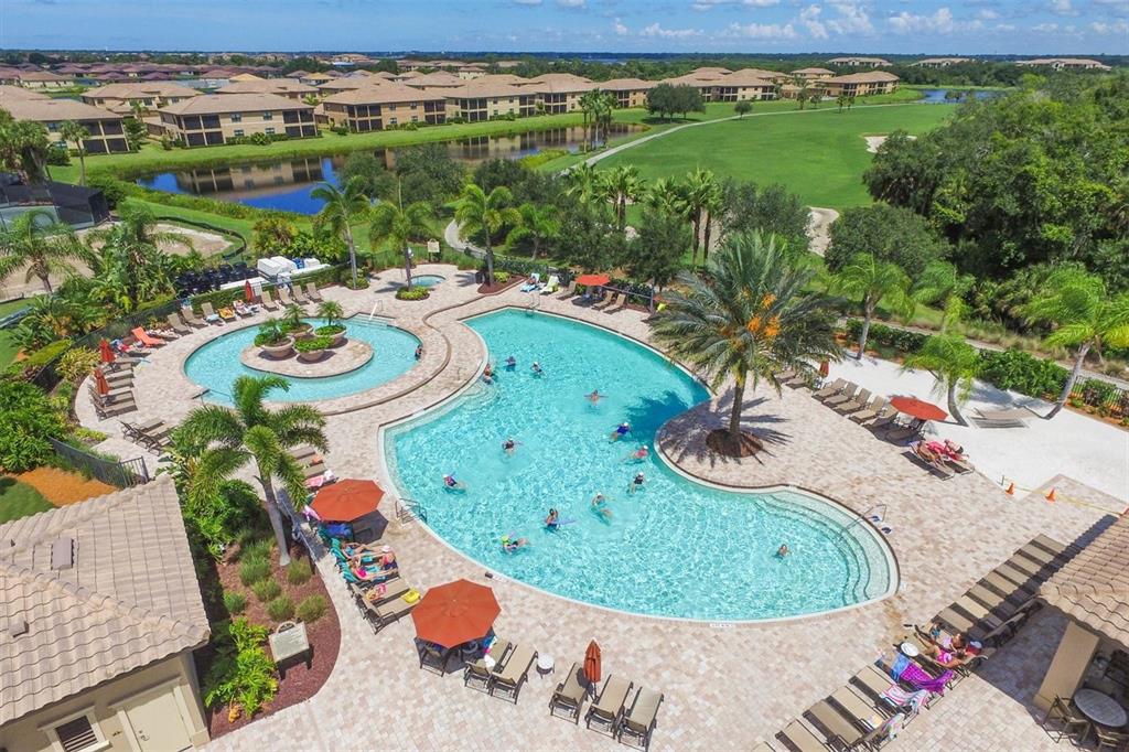 An aerial view of a community swimming pool surrounded by lounge chairs and palm trees — 6509 GRAND ESTUARY TRAIL UNIT 108, BRADENTON, FL