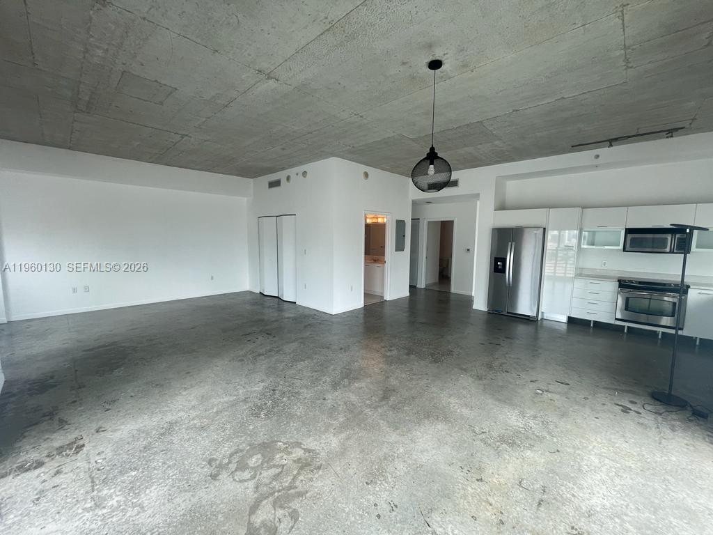 This open-concept living area features a concrete ceiling, polished concrete floors, and a kitchen — 133 NE 2 AVE # 1813, Miami FL 33132, MIAMI, FL