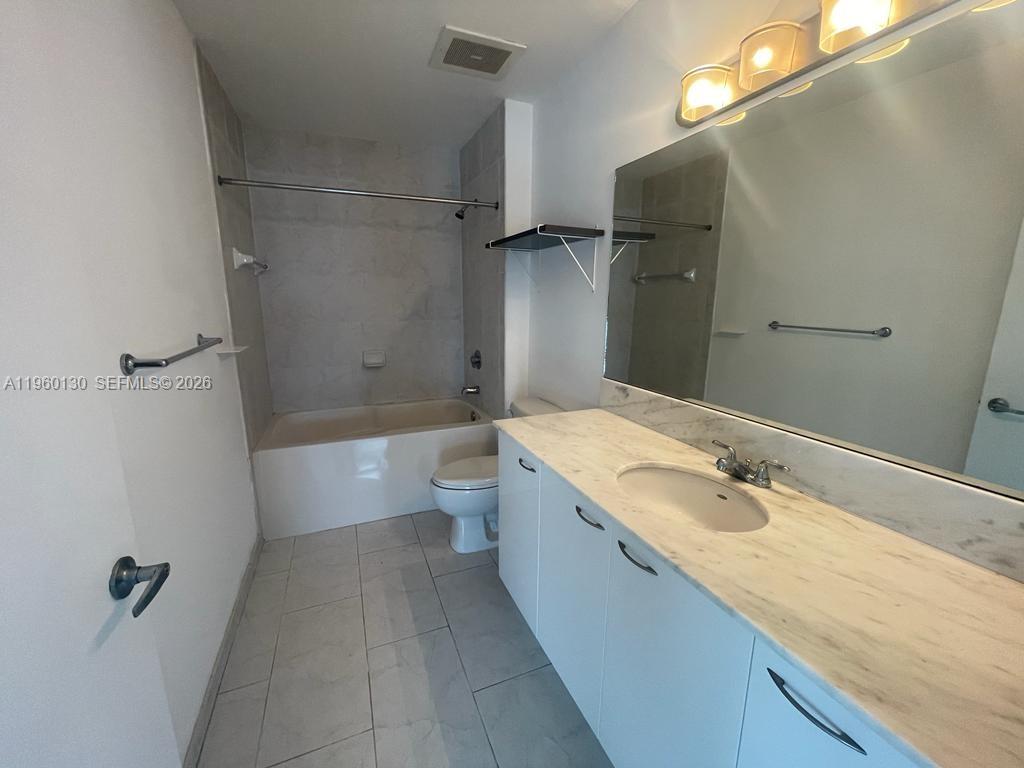 A bathroom features a white vanity with a marble countertop, a toilet, and a tub-shower — 133 NE 2 AVE # 1813, Miami FL 33132, MIAMI, FL