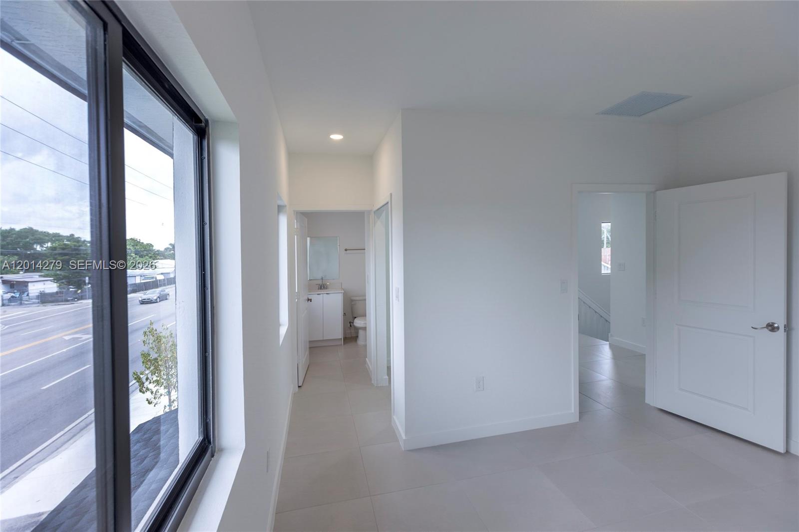 A bright, minimalist room features white walls, light tile flooring, and a view of a street — 9151 NW 32 Ave, Miami FL 33147, MIAMI, FL