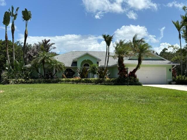A light green single-story house with a white garage and palm trees in the front yard — 246 SE Ashley Oaks Way, Stuart FL 34997, STUART, FL