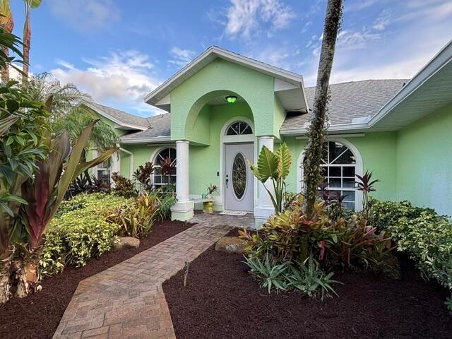 A light green house features a brick walkway leading to an arched front entryway — 246 SE Ashley Oaks Way, Stuart FL 34997, STUART, FL