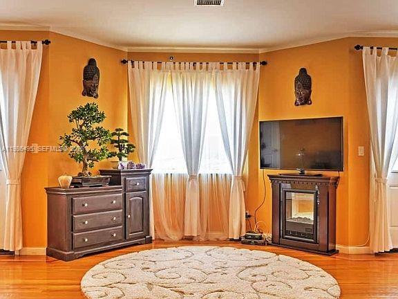 A living room features orange walls, a wooden dresser, a fireplace with a television, and curtains — 2841 Ford # 2, NY 11235, NY