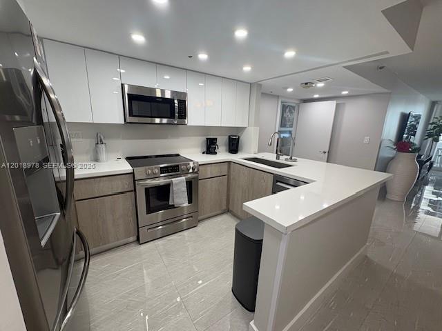 A modern kitchen features white upper cabinets, wood-tone lower cabinets, stainless steel appliances, and countertops — 1717 N Bayshore Dr # 1542, Miami FL 33132, MIAMI, FL