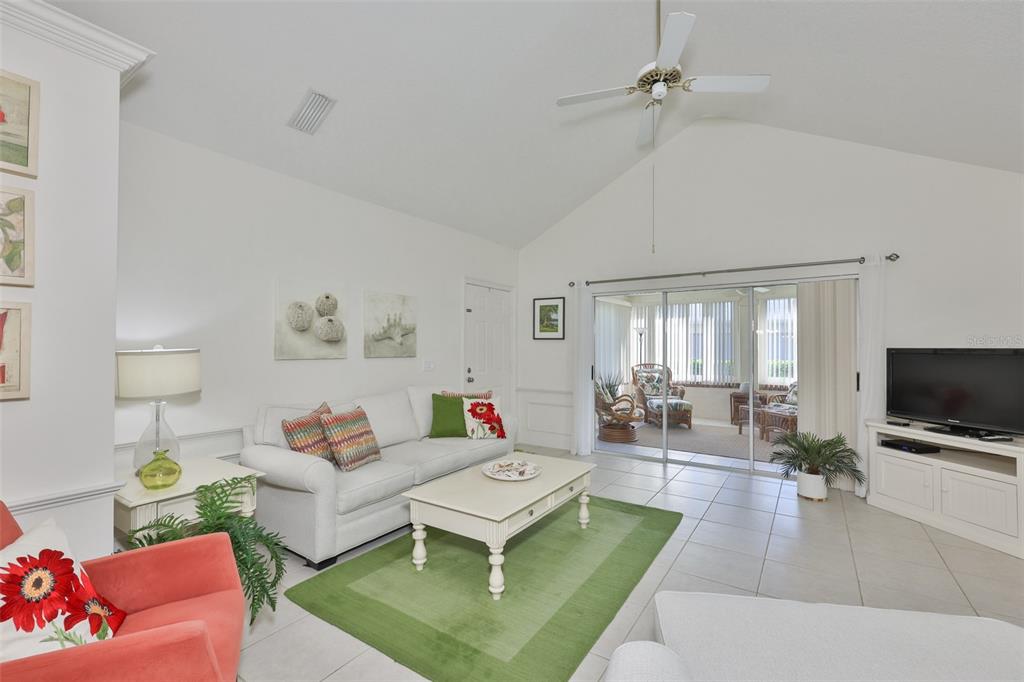 A living room with a white sofa, green area rug, and sliding doors to a lanai — 1115 GOLFVIEW WOODS DRIVE, SUN CITY CENTER, FL