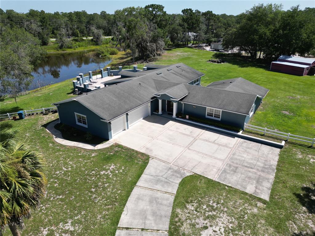 An aerial view shows a blue house with a multi-car garage and a backyard pool — 1313 RED PONY RANCH ROAD, DELAND, FL