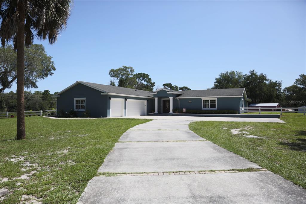 A blue single-story house with a two-car garage and a concrete driveway sits on grass — 1313 RED PONY RANCH ROAD, DELAND, FL