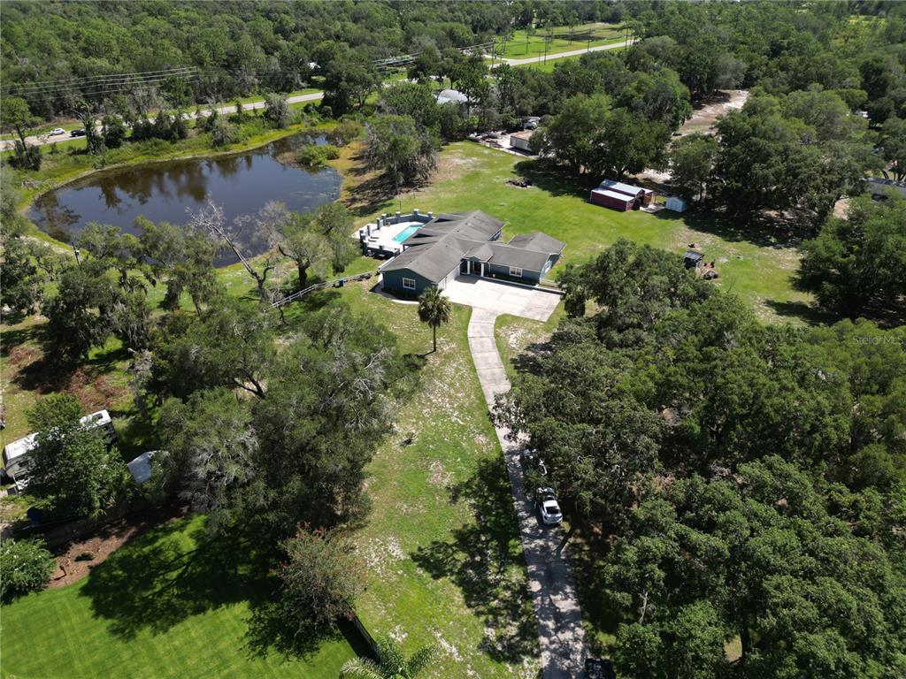 An aerial view shows a house with a pool, a pond, and a long driveway — 1313 RED PONY RANCH ROAD, DELAND, FL