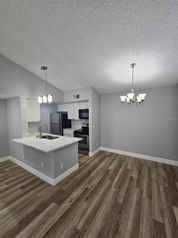A kitchen with white cabinets, granite countertops, and stainless steel appliances opens to a dining area — 5132 CONROY ROAD UNIT 932, ORLANDO, FL