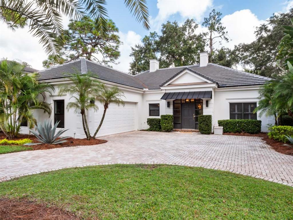 A single-story white house with a dark tiled roof, a brick driveway, and palm trees — 10457 CROMWELL GROVE TERRACE, ORLANDO, FL